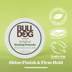 A container of Original Styling Pomade is shown with text highlighting natural shine and firm hold. Icons indicate its vegan approved, cruelty-free, contains argan oil, and is made for mens hair styling. The background is light green.