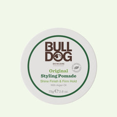 A white round container of Original Styling Pomade for men offers natural shine and firm hold with argan oil. The 75g (2.6 oz) lid displays the product name, logo, and its shine finish for easy hair styling.