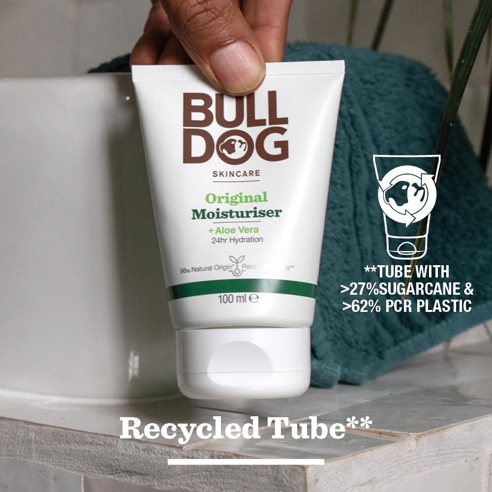 A hand holds a tube of Original Moisturiser for men, made with natural origin ingredients and featuring a “Recycled Tube” label. The packaging uses over 27% sugarcane and 62% post-consumer recycled plastic.