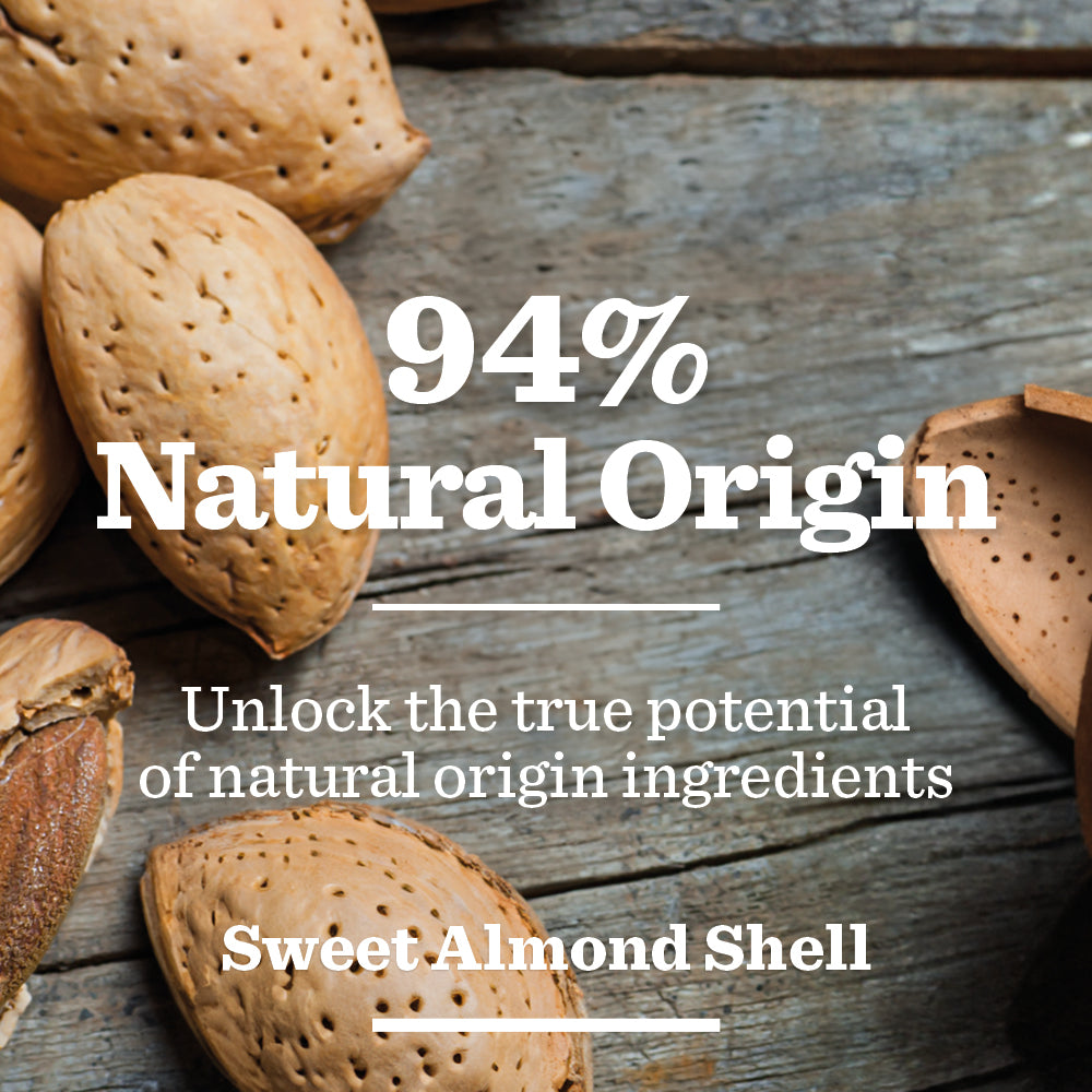 Whole and cracked almond shells on a wooden surface with text overlay: Original Face Scrub. Made with 94% natural origin ingredients, including Sweet Almond Shell for effective exfoliation.