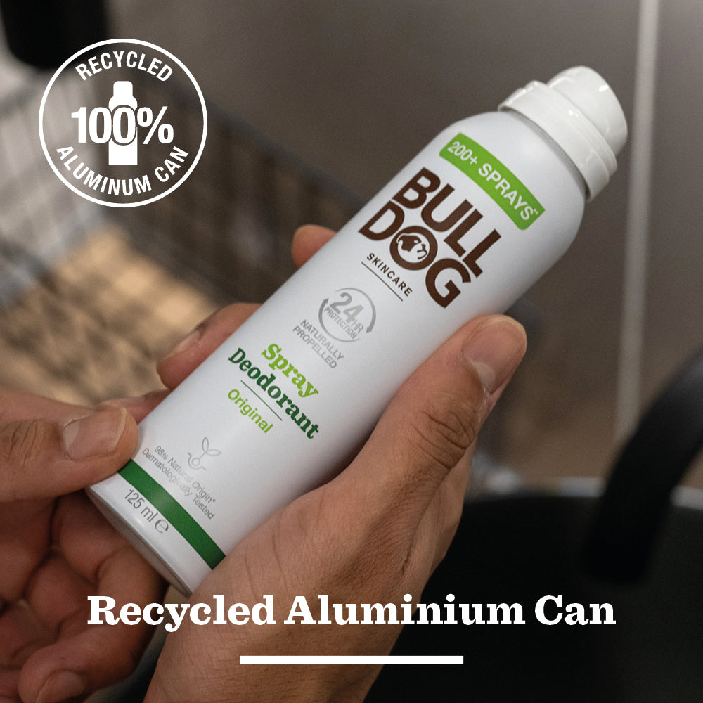 A person holds a can of Original Spray Deodorant, which features bold text about its 100% recycled aluminium can, odour-control technology, and over 200 sprays. This vegan deodorant blends sustainability with lasting freshness.