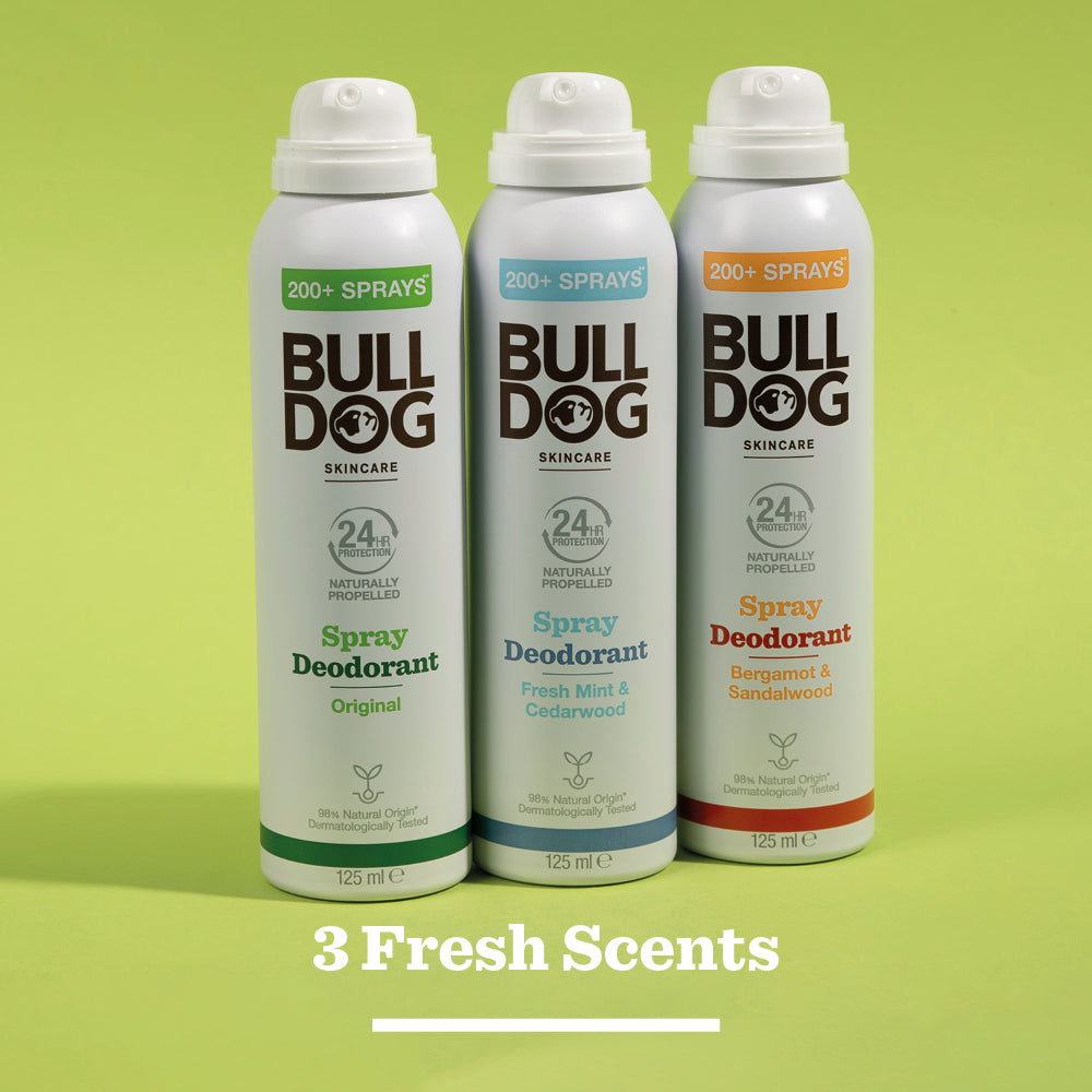 Three cans of Bulldog Skincare Original Spray Deodorant in Original, Fresh Mint & Cedarwood, and Bergamot & Sandalwood scents stand upright on a green background with 3 Fresh Scents below.