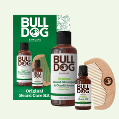 The BLDG Original Beard Care Kit 25 includes a green and white box with beard shampoo, conditioner, oil, and a wooden comb—all branded with the Bulldog Skincare logo. The ideal grooming set for any BLDG Beard enthusiast.
