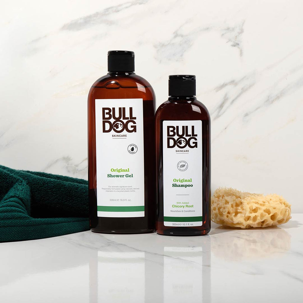 The Premium Body Care Bundle, featuring shower gel and shampoo, is shown on a white surface with a natural sponge and dark green towel against a white marble background.